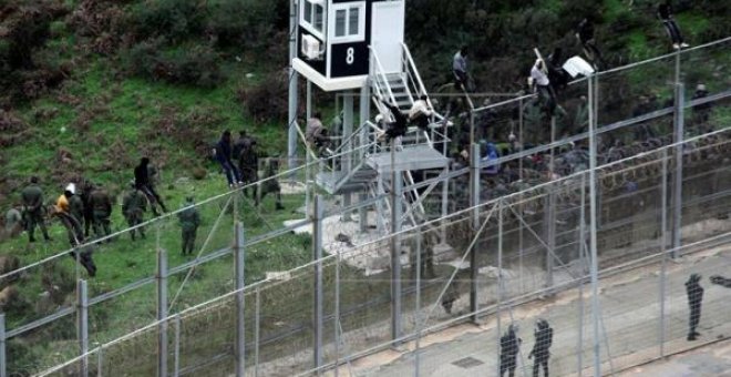 Varias personas migrantes intentan superar la valla fronteriza entre Ceuta y Marruecos, en una imagen de diciembre de 2017.-EFE