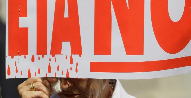 Un hombre solloza mientras sostiene una pancarta contra ETA en un minuto de silencio frente al Ayuntamiento de Madrid, tras un atentado de la organizacion terrorista en Mallorca en el que mató a dos guardias civiles, en julio de 2009. REUTERS/Susana Vera