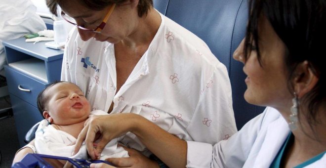 Una matrona toma el pulso a un recién nacido en un hospital. EFE