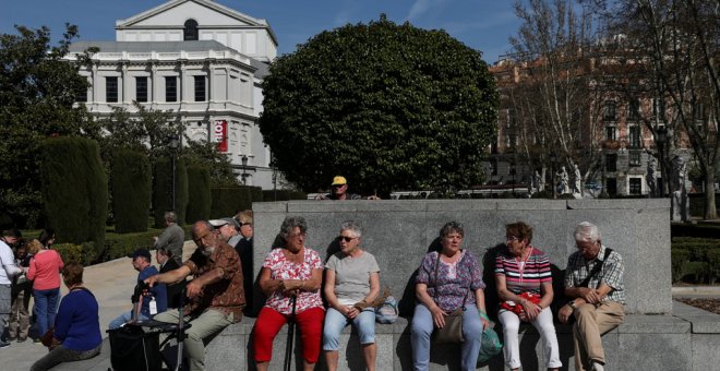 Varios turistas sentados cerca del Teatro de la Ópera, en el centro de Madrid. REUTERS/Susana Vera