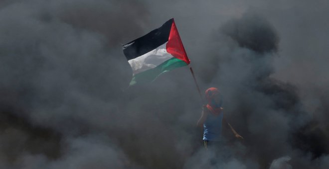 Un chico sostiene una bandera palestina en medio del humo durante las protestas contra el traslado de la embajada de EEUU a Jerusalén. / Reuters