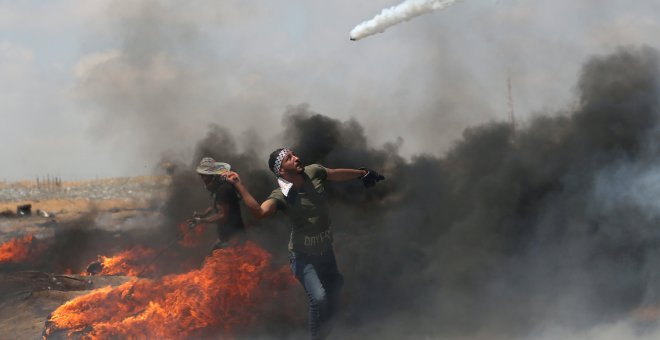 Un joven con una raqueta en la mano para alcanzar un bote de gas lacrimógeno en Gaza/Reuters