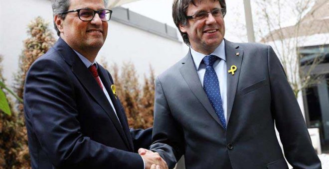 El recién elegido presidente de la Generalitat de Catalunya, Quim Torra (izq), estrecha la mano a su predecesor, el expresidente regional catalán Carles Puigdemont, en Berlín. (OMER MESSINGER | EFE)