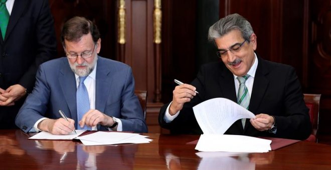 El presidente del Gobierno, Mariano Rajoy (i), y el de Nueva Canarias, Román Rodríguez (d), firmaron hoy en Las Palmas de Gran Canaria el acuerdo por el que la formación nacionalista apoyará los Presupuestos Generales del Estado 2018 a cambio de diversas