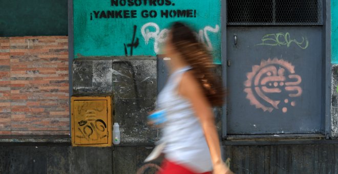 Mujer camina frente al mensaje de una de las paredes de Caracas - REUTERS