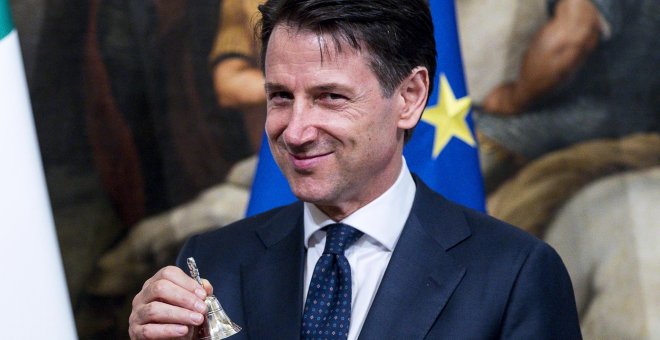 El nuevo primer ministro italiano, Giuseppe Conte, posa con una pequeña campana de plata entregada por el ahora exprimer ministro Paolo Gentiloni (no aparece) para abrir el primer Consejo de Ministros en el Palacio de Chigi, en Roma. EFE