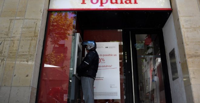 Un hombre saca dinero de un cajero automático del Banco Popular, en la localidad barcelonesa de Vilanova i la Geltru, en una foto del 7 de junio de 2017, el día que se anunció la resolución de la entidad. AFP/Lluis Gené