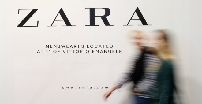 Un par de personas pasan por delante de un anuncio de una tienda de Zara, la principal enseña de Inditex, en Milán. REUTERS/Alessandro Garofalo