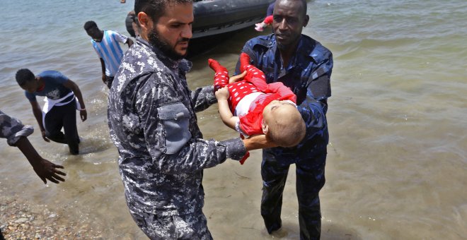 Guardacostas libios sostienen los cadáveres de tres bebés fallecidos en el naufragio frente a las costas libias. Hay cien desaparecidos y 16 supervivientes.- AFP/ MAHMUD TURKIA