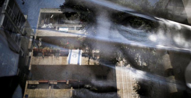 Una bandera de Israel aparece reflejada en la foto del Primer Ministro Netanyahu. REUTERS/Corinna Kern