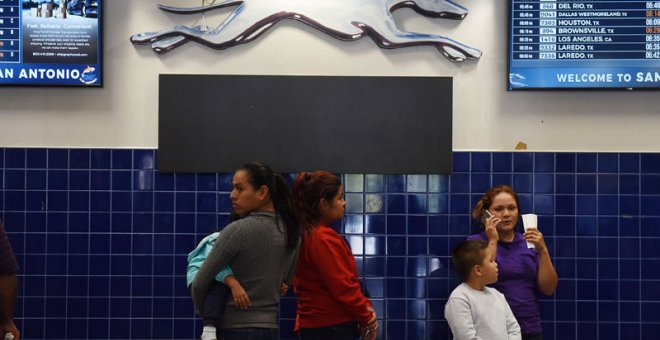 Unas madres y sus hijos esperan el autobús tras ser liberados se un centro de San Antonio (Texas). (REUTERS)