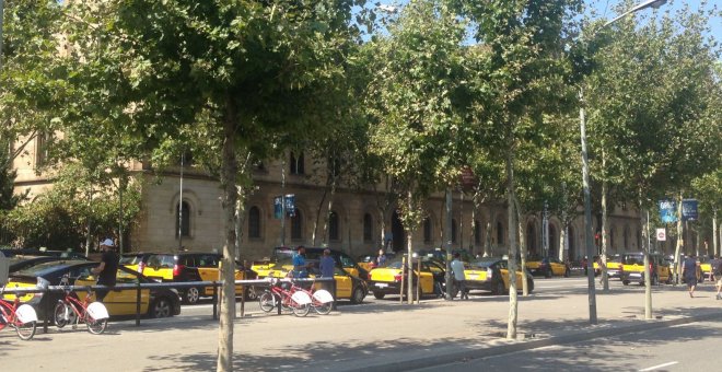 Taxistes en marxa lenta pels carrils centrals de la Gran Via de Barcelona, a l'alçada de Plaça Universitat. Alguns d'ells, fora dels seus vehicles. / Laia Cugota