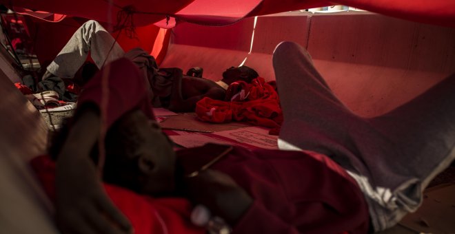 Dos migrantes se protegen del sol bajo una manta en el puerto del Algeciras. Han pasado varias noches allí debido al colapso en los polideportivos y dependencias policiales tras llegar en patera a España. JAIRO VARGAS