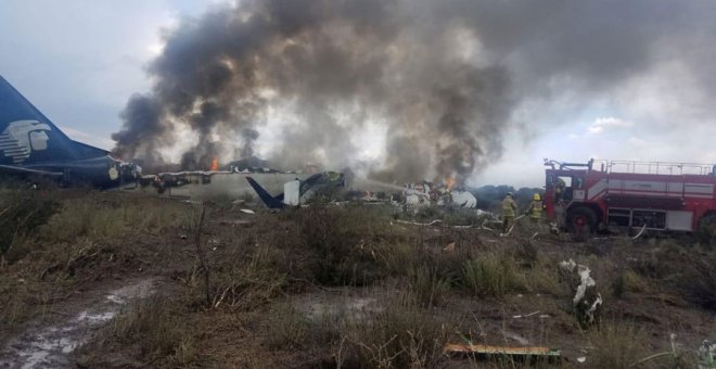 Los bomberos tratan de apagar el incendio en el avión accidentado en México. REUTERS