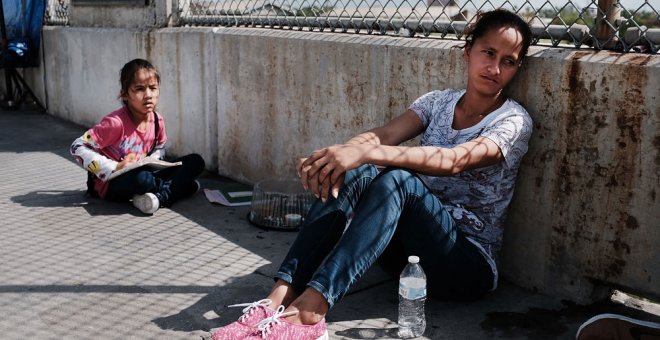 Una mujer hondureña y su hija que huyen de la violencia y la pobreza esperan en la frontera con EEUU tras haberles sido rechazada la entrada. SPENCER PLATT (AFP)