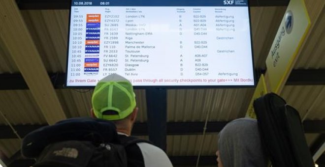 Una pareja observa una pantalla en la que se muestra información sobre los vuelos durante la huelga de 24 horas convocada por los pilotos de Ryanair en el aeropuerto de Berlín (Alemania)  EFE/ Hayoung Jeon