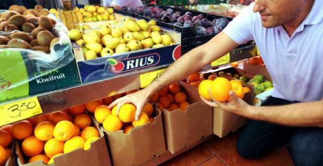 Un hombre al lado de unas naranjas en una frutería. EFE/Elvira Urquijo A.