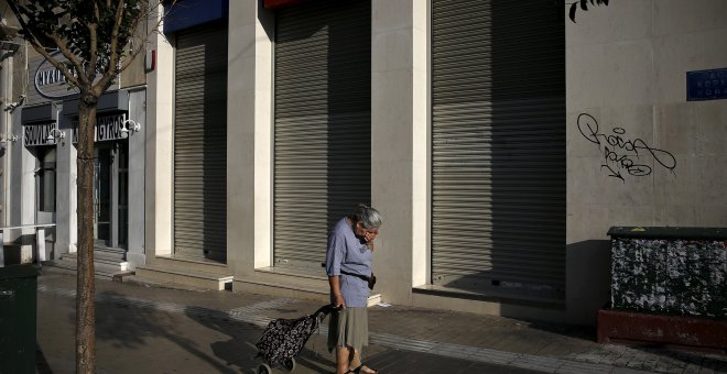 Una mujer con un carrito de la compra frente a una sucursal de Eurobank cerrada en Atenas, en una imagen de archivo. REUTERS / ALKIS KONSTANTINIDIS
