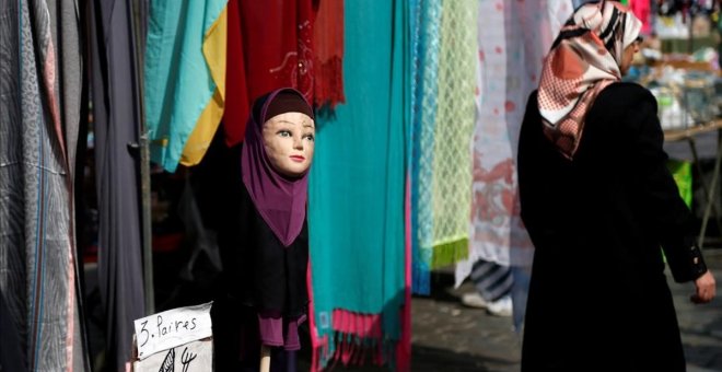 Una mujer con velo pasa junto a una tienda de venta de pañuelos en una imagen de archivo. / REUTERS - FRANCOIS LENOIR