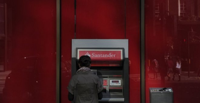 Una mujer utiliza un cajero automático en una oficina del Banco Santander en el centro de Londres. AFP/Carl Court