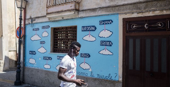 Un hombre pasa junto a un mural en Riace. - GIACOMO SINI