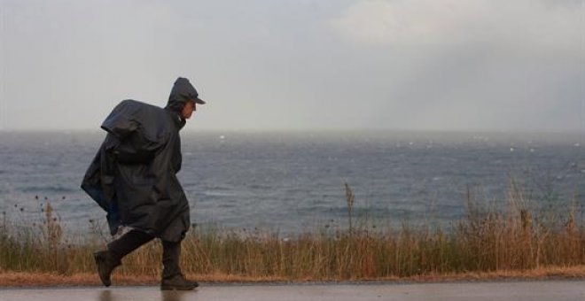 Siete provincias en alerta por riesgo de lluvias y fuertes oleajes en las zonas costeras. Peregrinos del Camino de la Costa realizan la travesía cubiertos para ampararse de la lluvia y del frío. EFE
