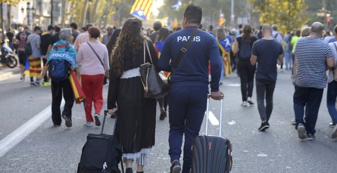 Dos turistas con sus maletas por una calle de Barcelona en la que marcha una manifestación independentista. AFP/Josep Lago