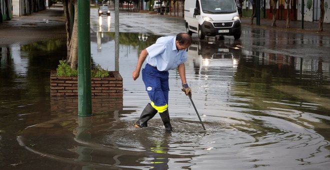 Un trabajador achicando el agua en mitad de la acera en Málaga./EFE