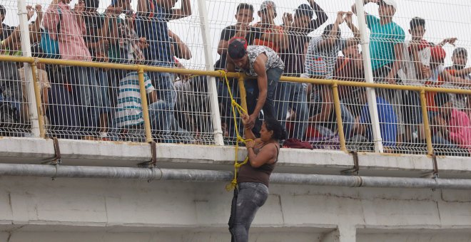 Una migrante trata de escalar el puente que cruza el río que une México con Honduras.REUTERS/Edgard Garrido