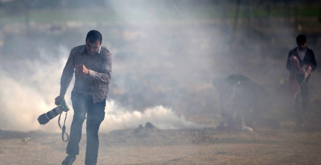 Un fotógrafo palestino trata de evitar el gas lacrimógeno lanzado por las fuerzas israelís. MOHAMMED ABED/AFP/Archivo