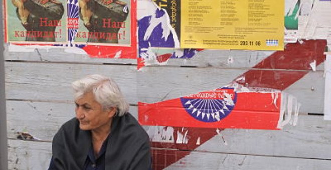 Una mujer descansa junto a carteles de propaganda electoral