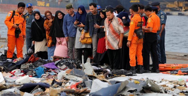Familiares de los pasajeros del avión estrellado observan las pertenencias de las víctimas - REUTERS/Beawiharta