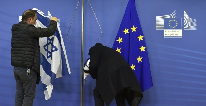Empleados de la Comisión Europea retiran la bandera israelí en Bruselas, en una imagen de archivo. / AFP - JOHN THYS