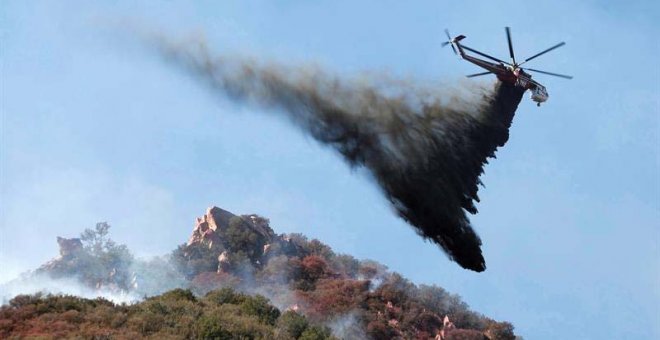 Un helicóptero descarga agua sobre un incendio forestal  en Malibú, California. (MIKE NELSON | EFE)