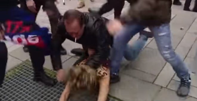 Captura del vídeo de 'Euronews' en donde se aprecia a un ultraderechista pateando en el suelo a una de las activistas de femen a la que otro fascista inmoviliza de cara al suelo | Euronews