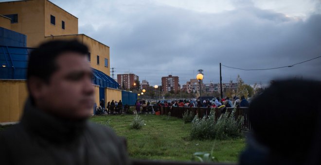 Cientos de solicitantes de asilo esperan la cola durante toda la noche para obtener un cita previa con la que comenzar sus trámites, en la comisaría de Extranjería de Aluche, Madrid. JAIRO VARGAS