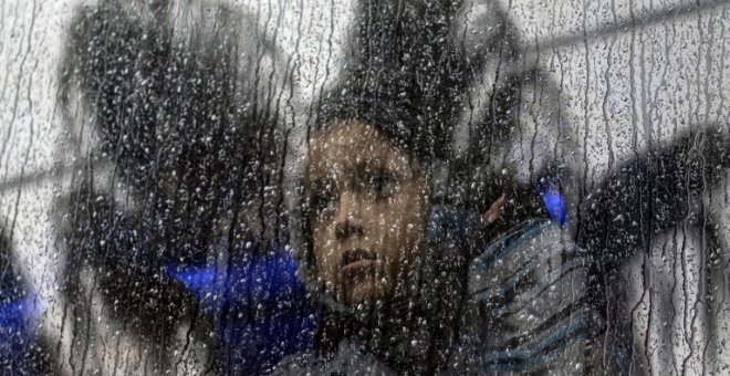 Una niña centroamericana que viaja en una caravana de migrantes, toma un autobús fuera de un refugio temporal en el este de Tijuana, México, el 6 de diciembre de 2018 | Guillermo Arias/AFP