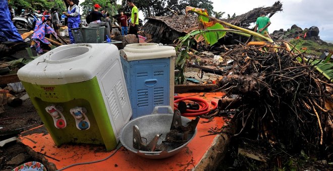 Varias personas tratan de buscar víctimas entre los escombros de una casa destruida por el paso del tsunami./ REUTERS