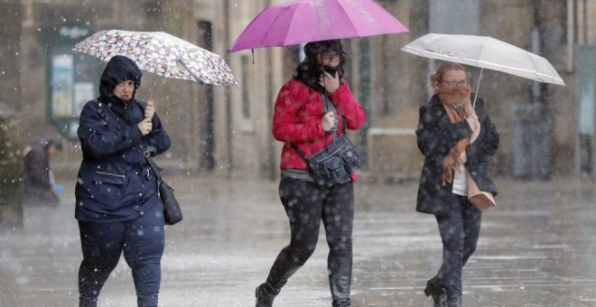 Imagen de archivo de varias personas transitan bajo la lluvia la plaza del Obradoiro, en Santiago de Compostela/EFE