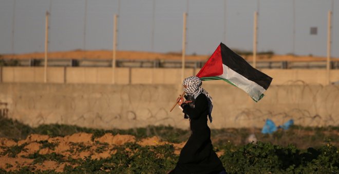 Una mujer con la bandera palestina en una protesta contra Israel en la frontera con Gaza. REUTERS/Ibraheem Abu Mustafa