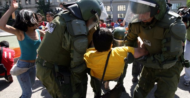 Policías antidisturbios arrestan en 2008 a un activista durante una manifestación donde indígenas mapuche tiñeron el agua de la fuente frente al rojo de La Moneda (Santiago),  simbolizando la muerte de un mapuche. / AFP - MARTIN BERNETTI