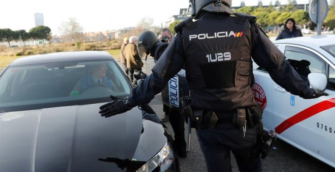 Efectivos de la Policía Nacional entre un vehículo de licencia VTC y un taxi a las puertas del recinto ferial de Ifema. EFE/Chema Moya