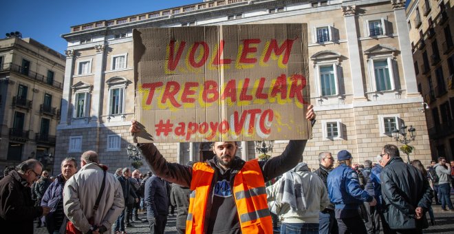 Un conductor de VTC porta un cartel con la consigna "Volem Treballar #apoyoVTC" en la Plaza de Sant Jaume - David Zorrakino/ EP