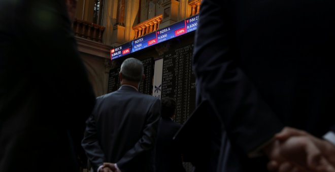 Varias personas atienden los paneles informativos en el patio de negociación de la Bolsa de Madrid. REUTERS/Susana Vera