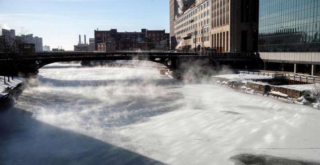 Varias personas cruzan un puente mientras la niebla se eleva desde el río Chicago. (KAMIL KRZACZYNSKI | EFE)