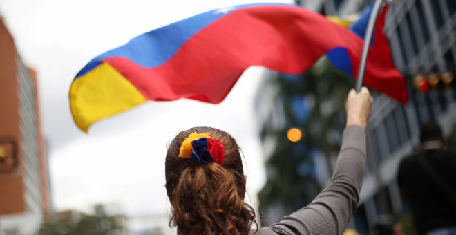 Una mujer ondea una bandera de Venezuela durante una manifestación en contra de Nicolás Maduro. / REUTERS - ANDRES MARTINEZ CASARES