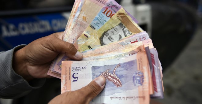 Un hombre cuenta bolívares en una calle de Caracas el 29 de enero de 2019 | AFP/Luis Robayo