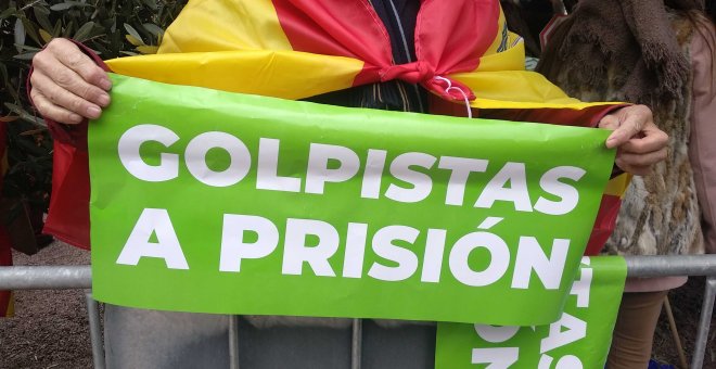 Una mujer sujeta un cartel de color verde en el que se puede leer: "Golpistas a prisión".