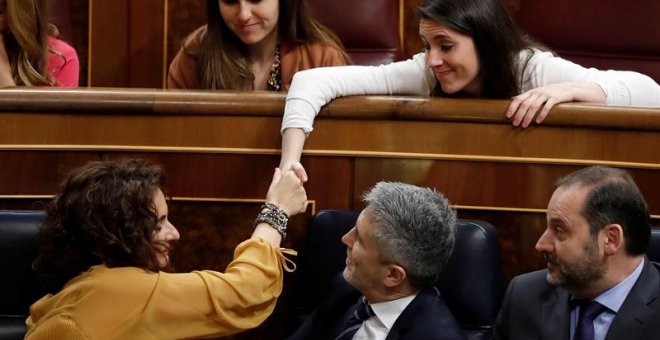 La ministra de Hacienda, María Jesús Montero (i - 1ªfila), estrecha la mano con la portavoz de Podemos en el Congreso, Irene Montero (d - 2ª fila), durante su intervención en la segunda jornada del debate de las enmiendas a la totalidad del proyecto de Pr