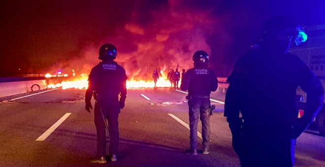 Mossos d'Esquadra observan una barricada en la AP-7. (PILAR SUÁREZ | REUTERS)